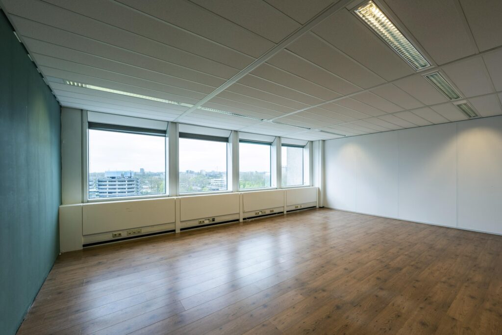 Empty office space with large windows and wooden flooring at Laan van Kronenburg.